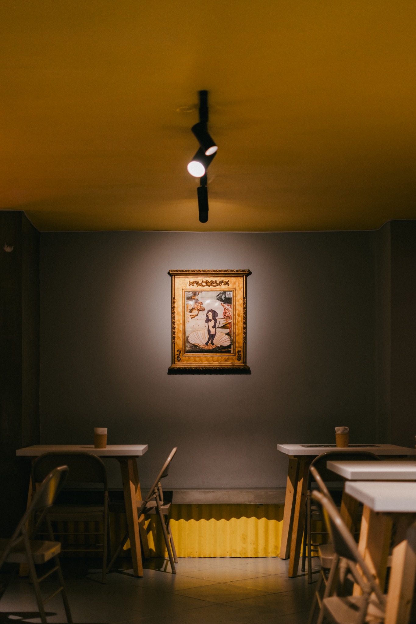 Interior de La Pate con mesas y una ilustración del Chori enmarcada